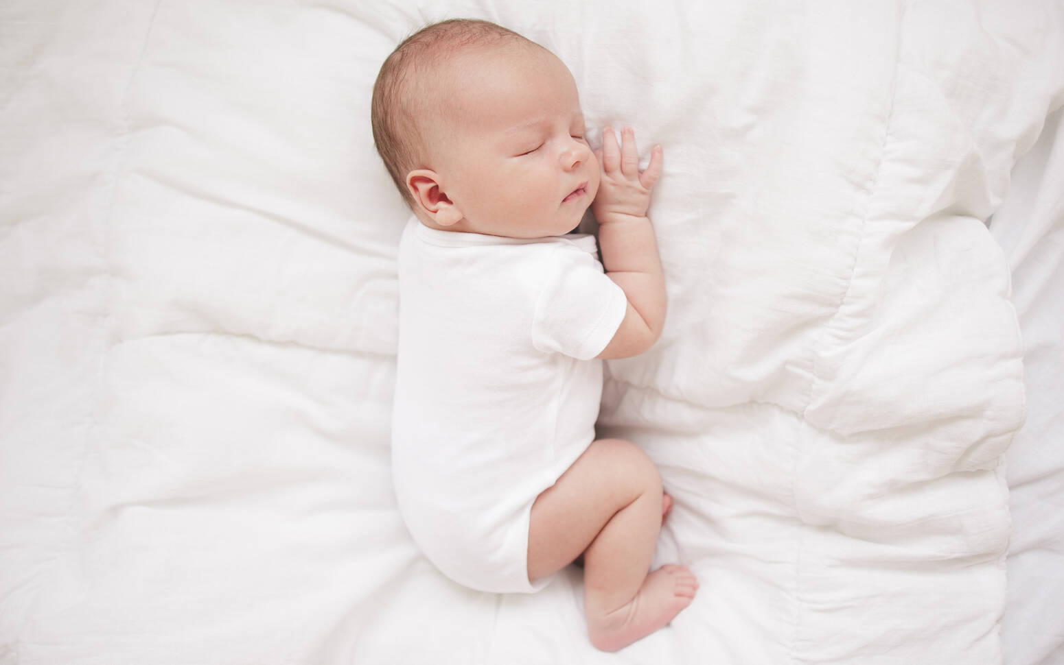 Newborn sleeping on bed
