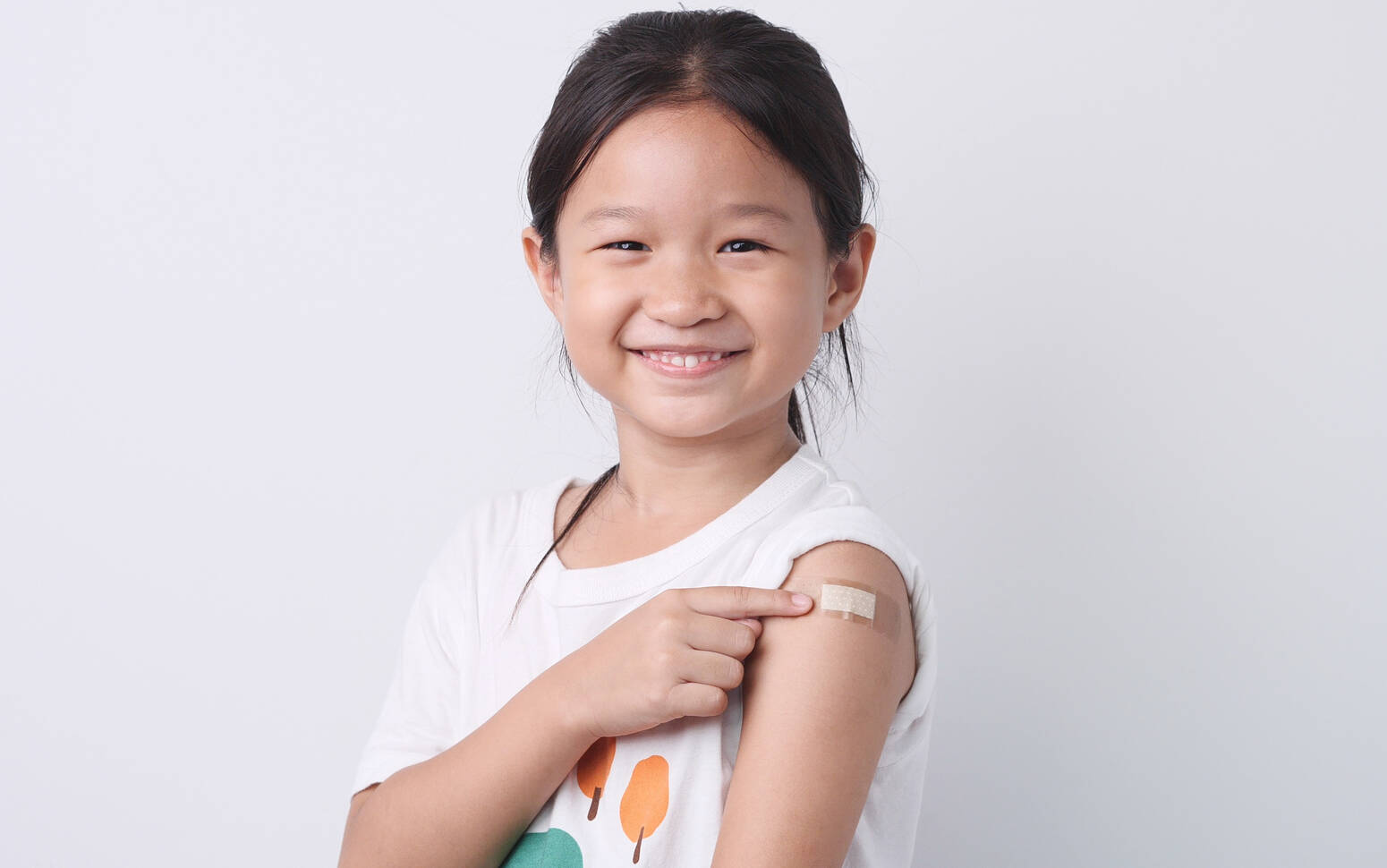 girl smiling pointing to band aid on arm