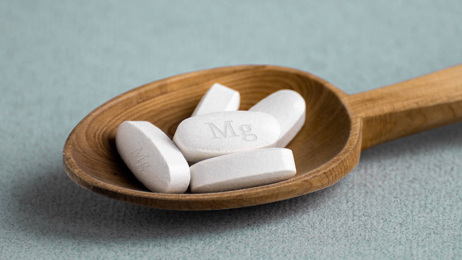 wooden spoon holding Magnesium pills