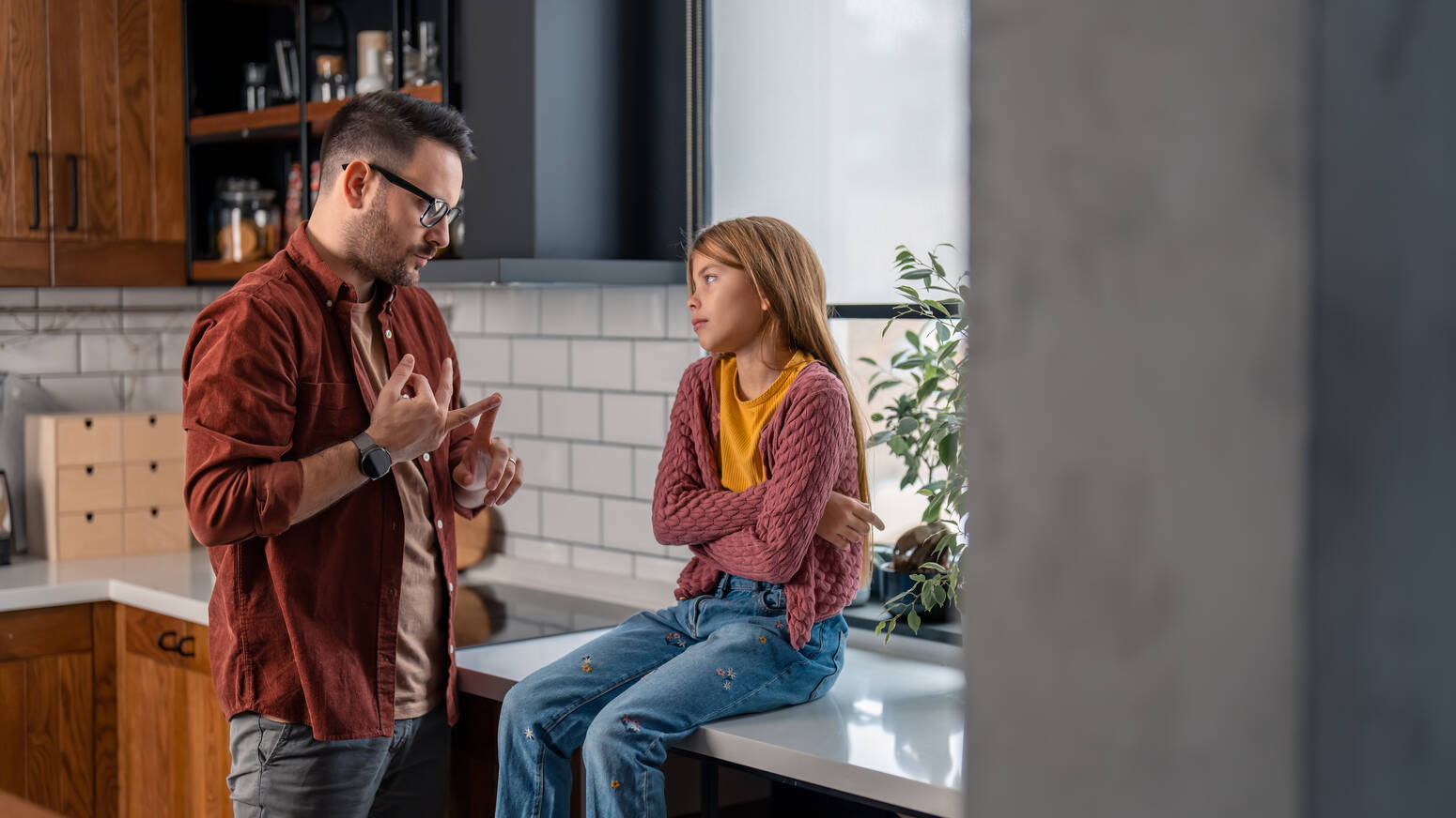 Child sitting on kitchen counter while parent talks to them