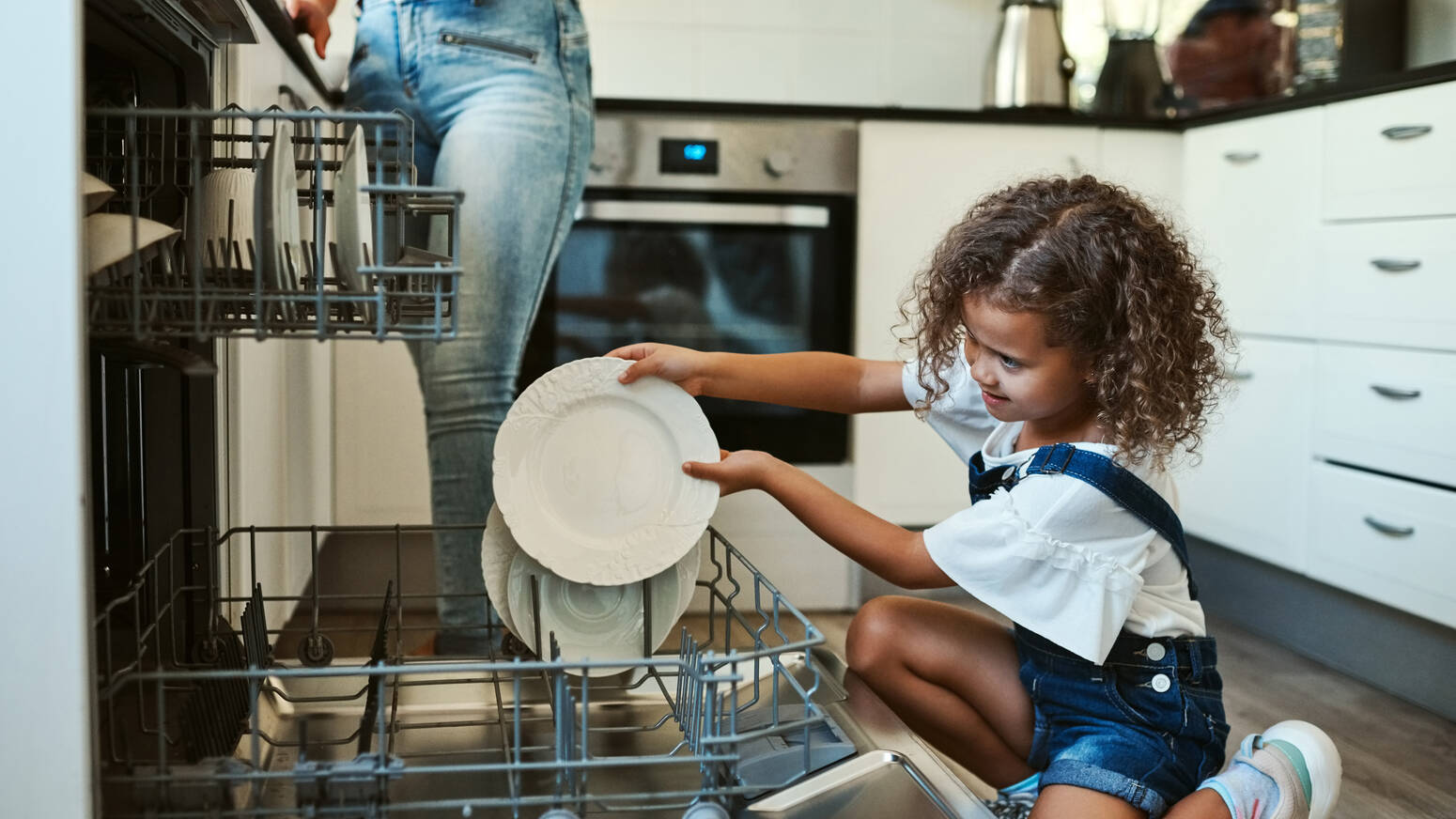 kid loading plates into dishwasher