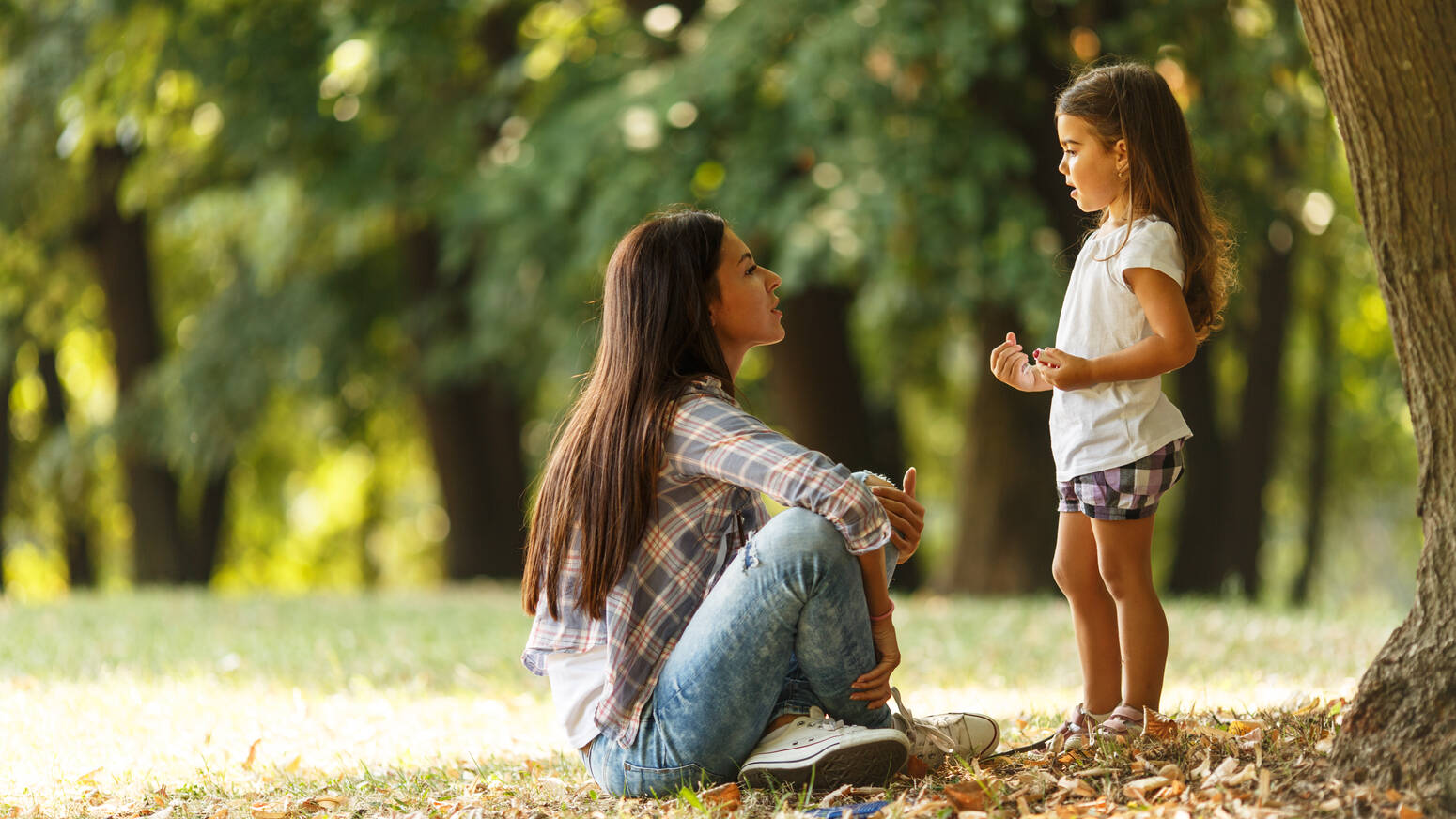 Adult sitting on ground child stand in front 