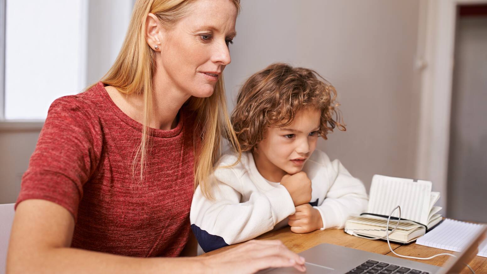 mom and child sitting at a table on a computer