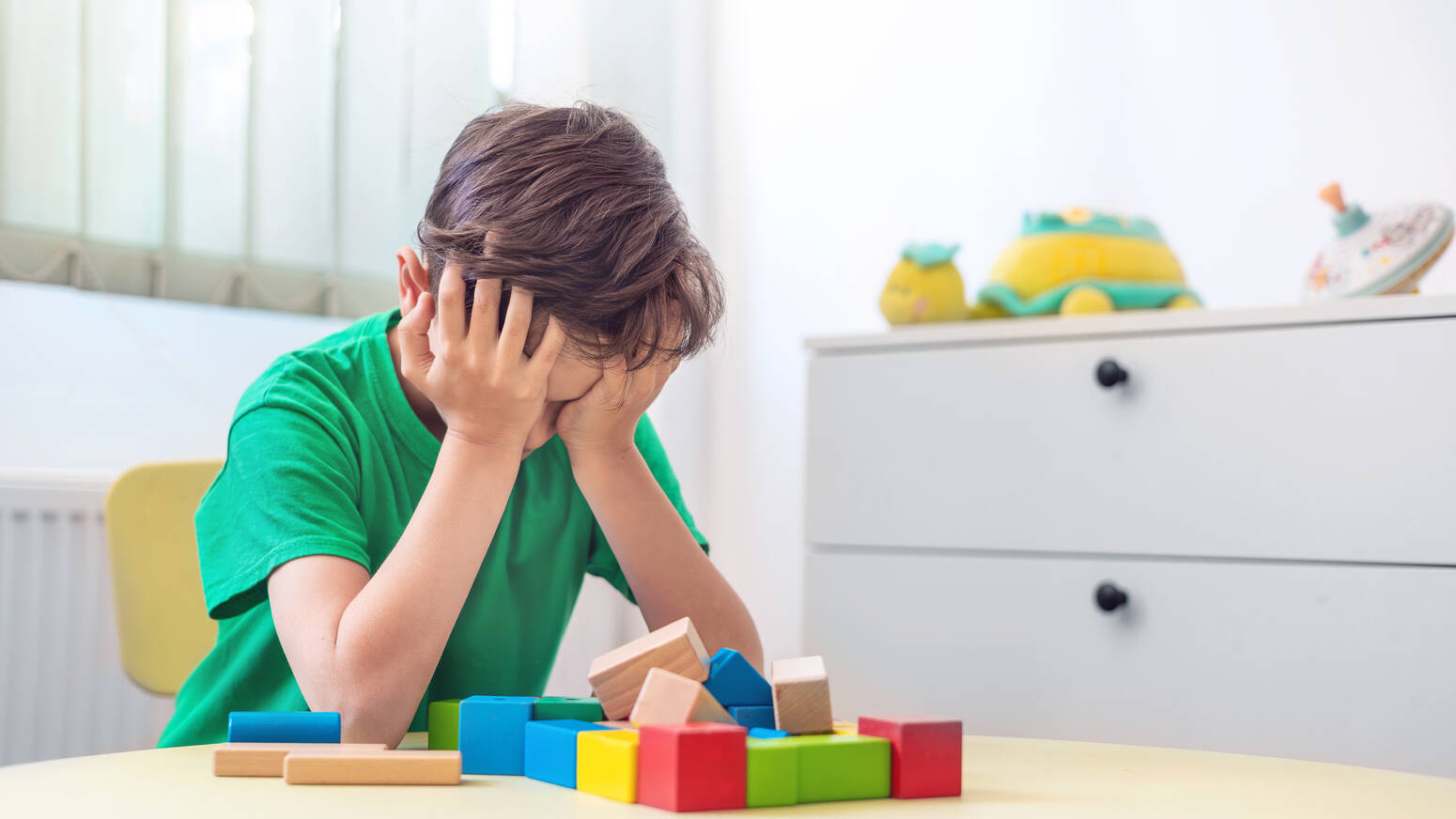 distressed kid at table with blocks