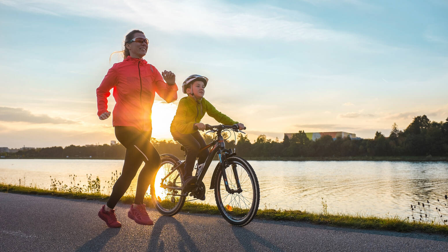 mom running with son on bik in sunset