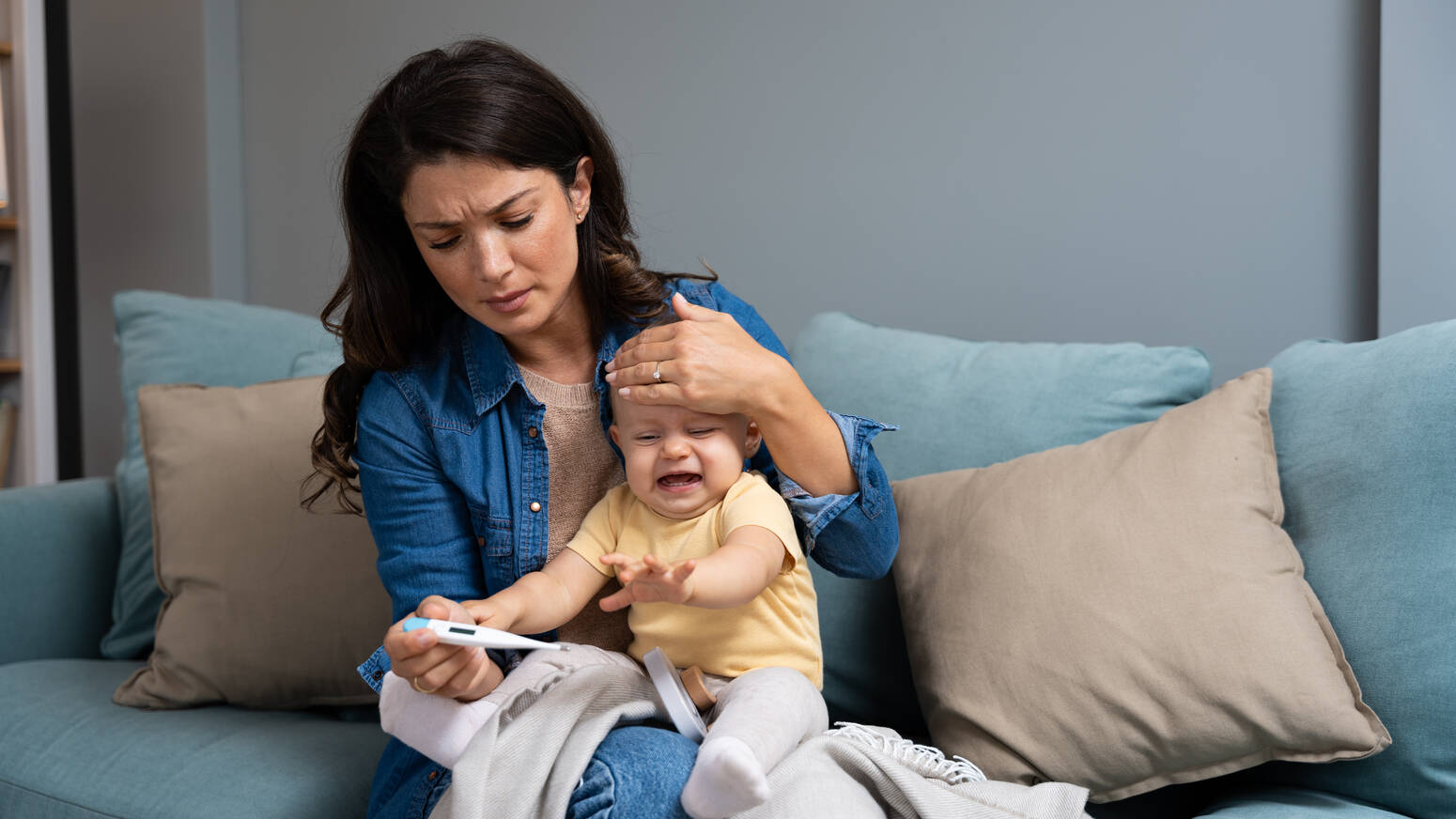 mom checking thermometer and comforting sick child