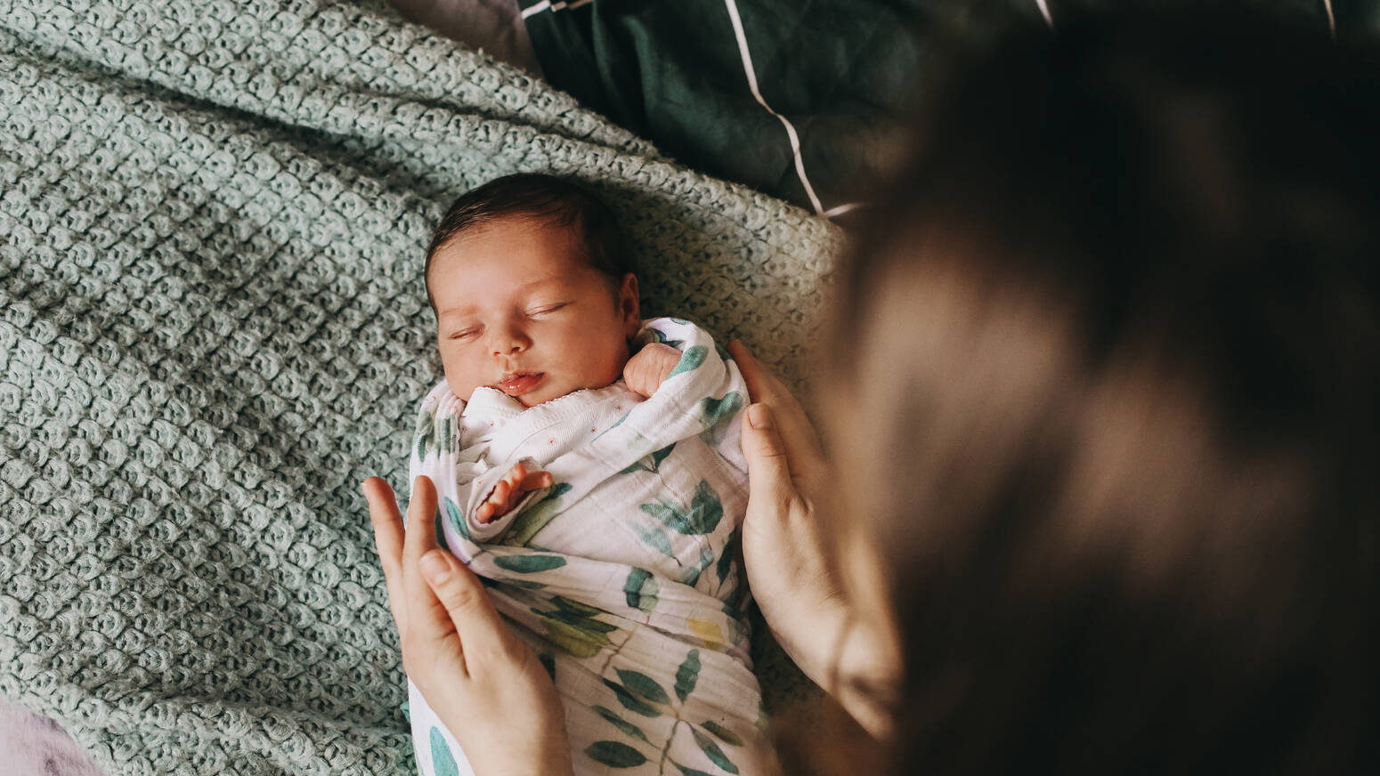 mom looking at swaddled newborn baby from above