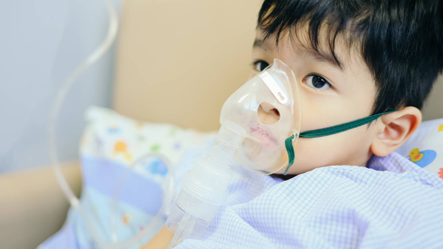 child in hospital bed with breathing mask