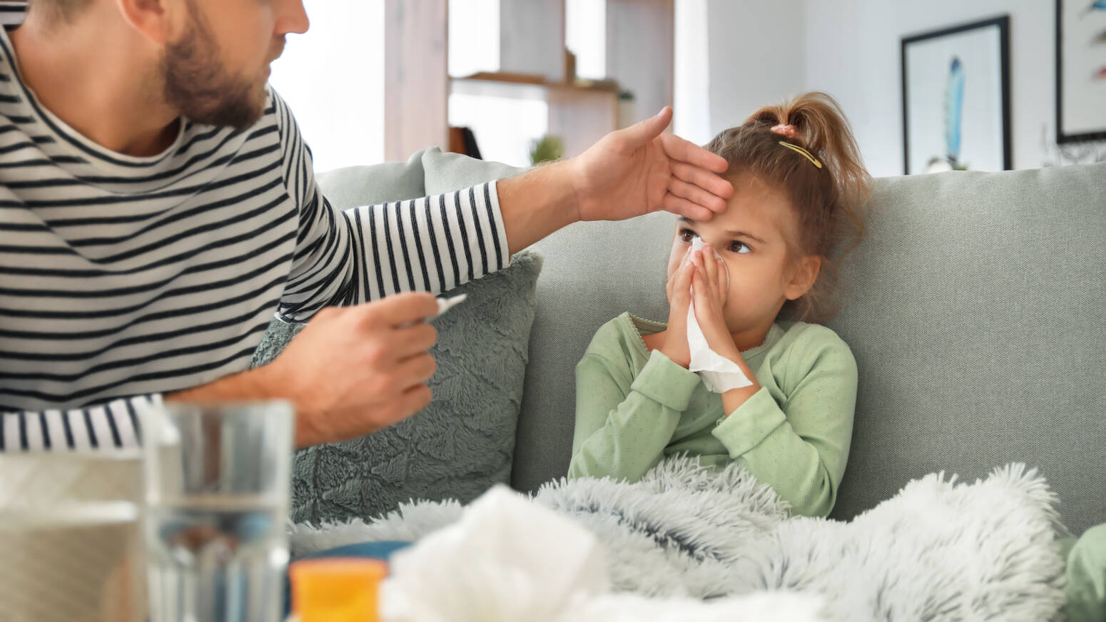 dad feeling young girls forehead who appears sick