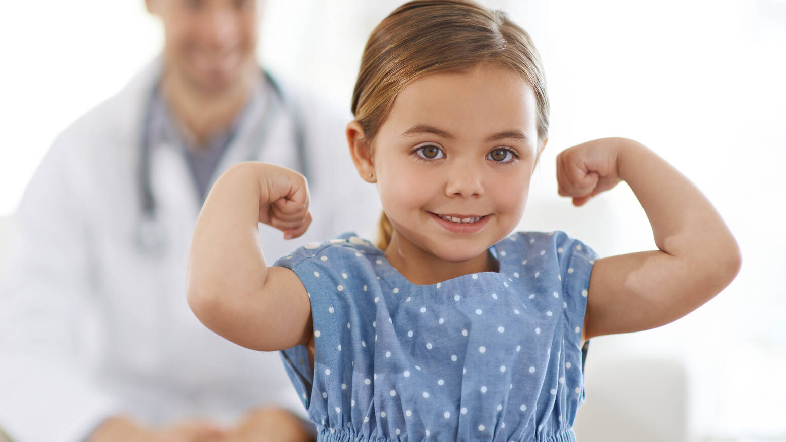 young girl showing arm muscles at doctor