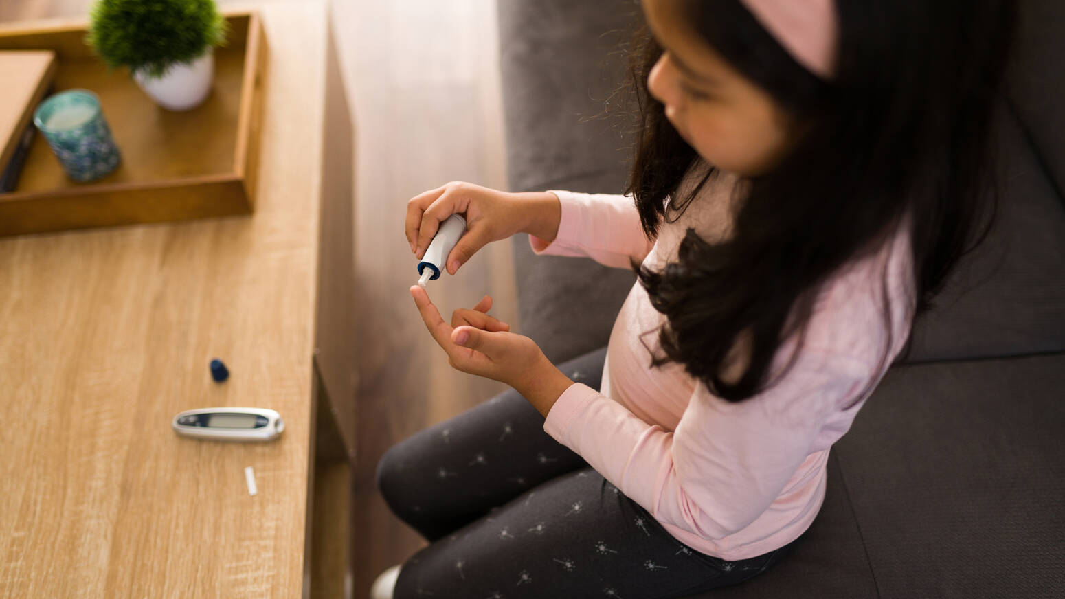 girl sitting at desk testing blood sugar