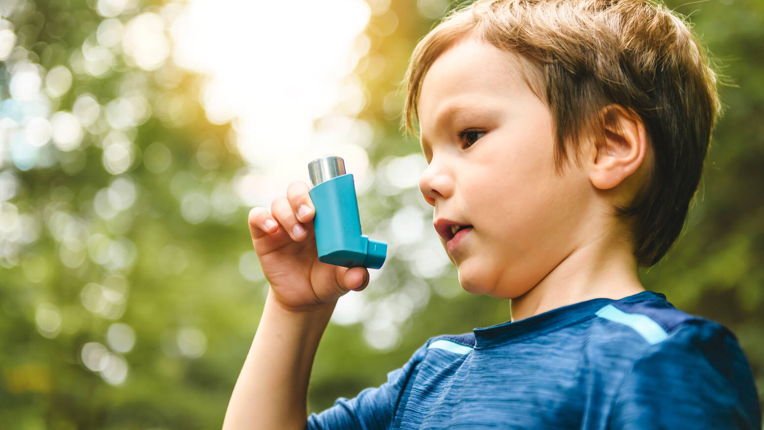 young boy outside holding inhaler