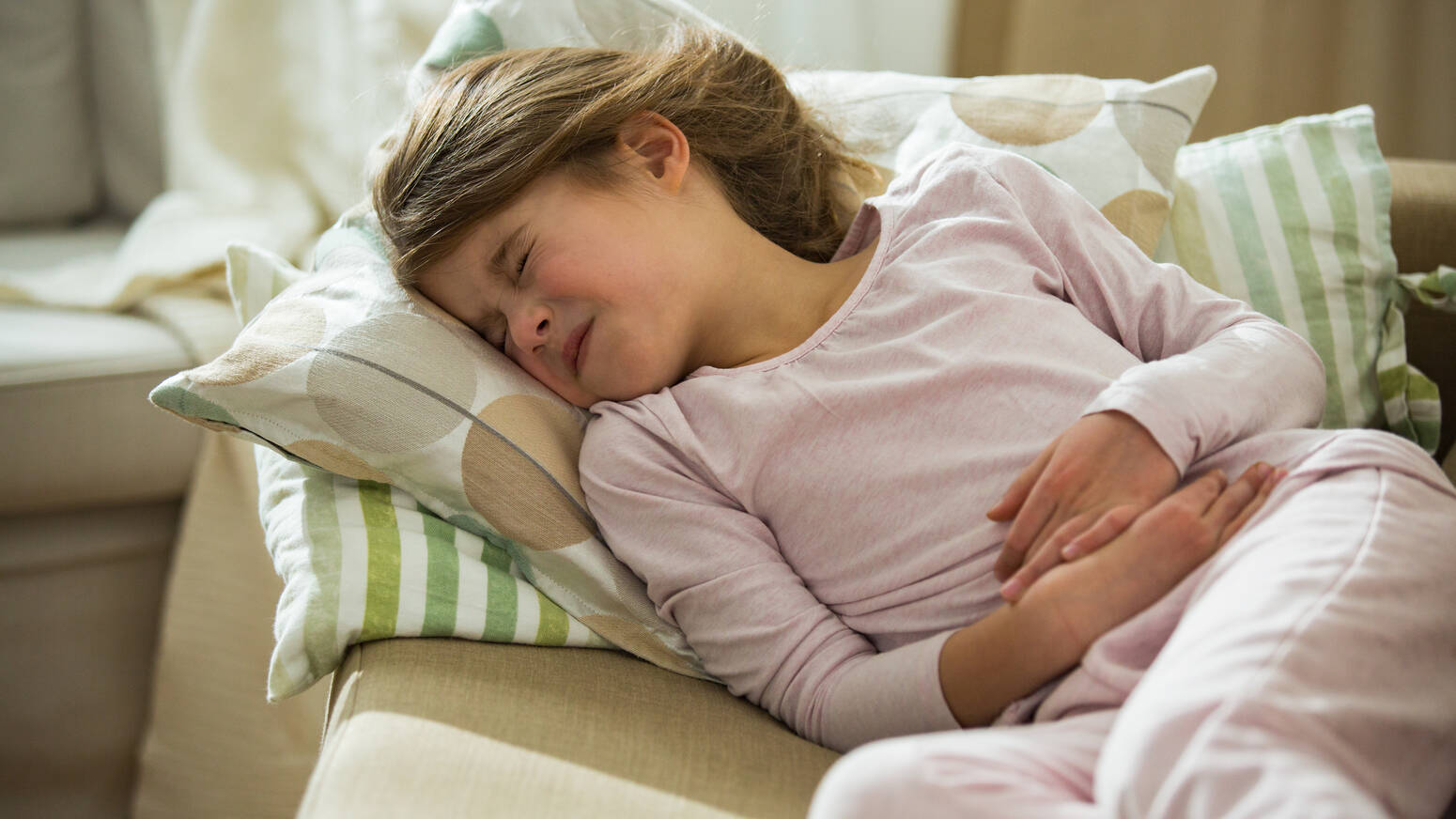 young girl on couch holding her stomach