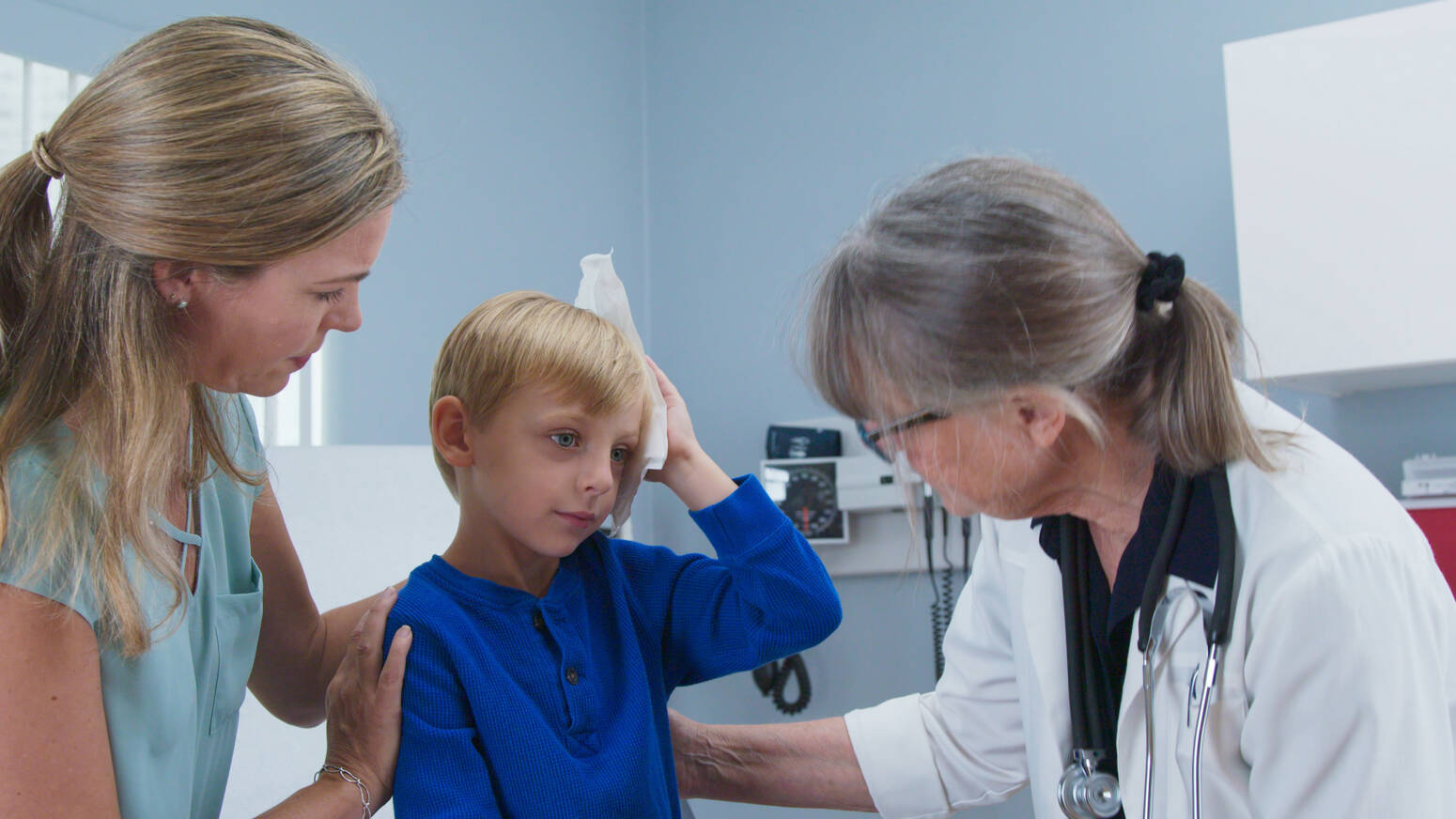 kid at doctor holding head