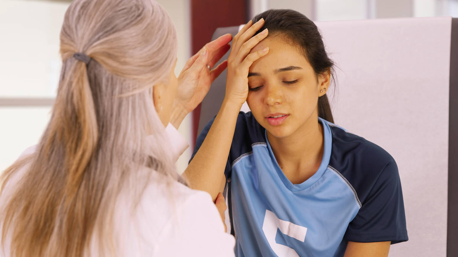 teenage girl holding head with adult