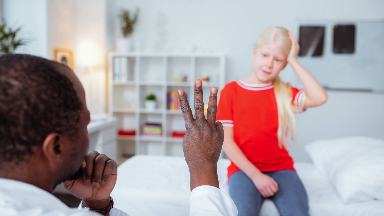 Doctor holding up fingers to girl with head injury