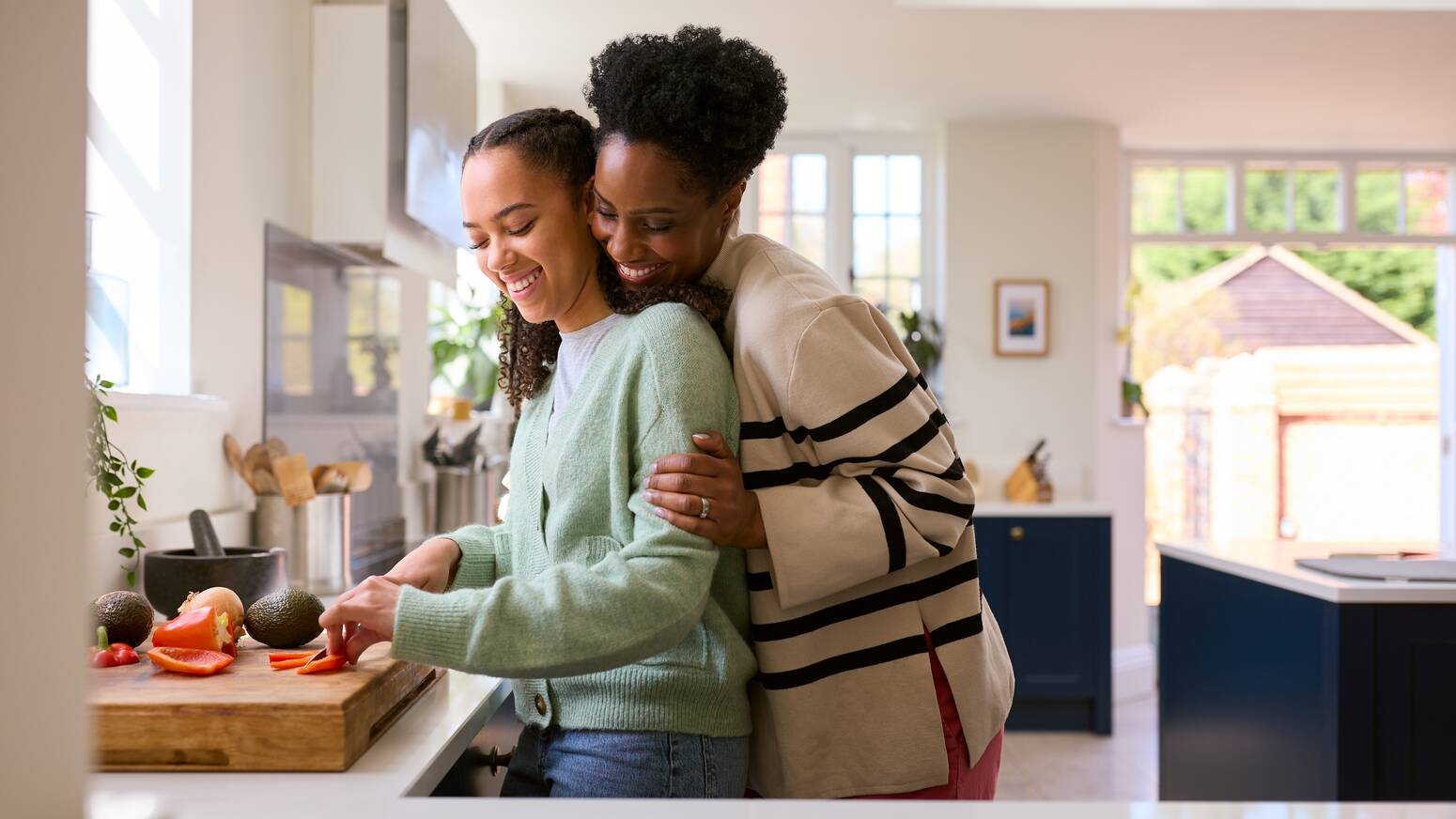 mom with arms around daughter in kitchen