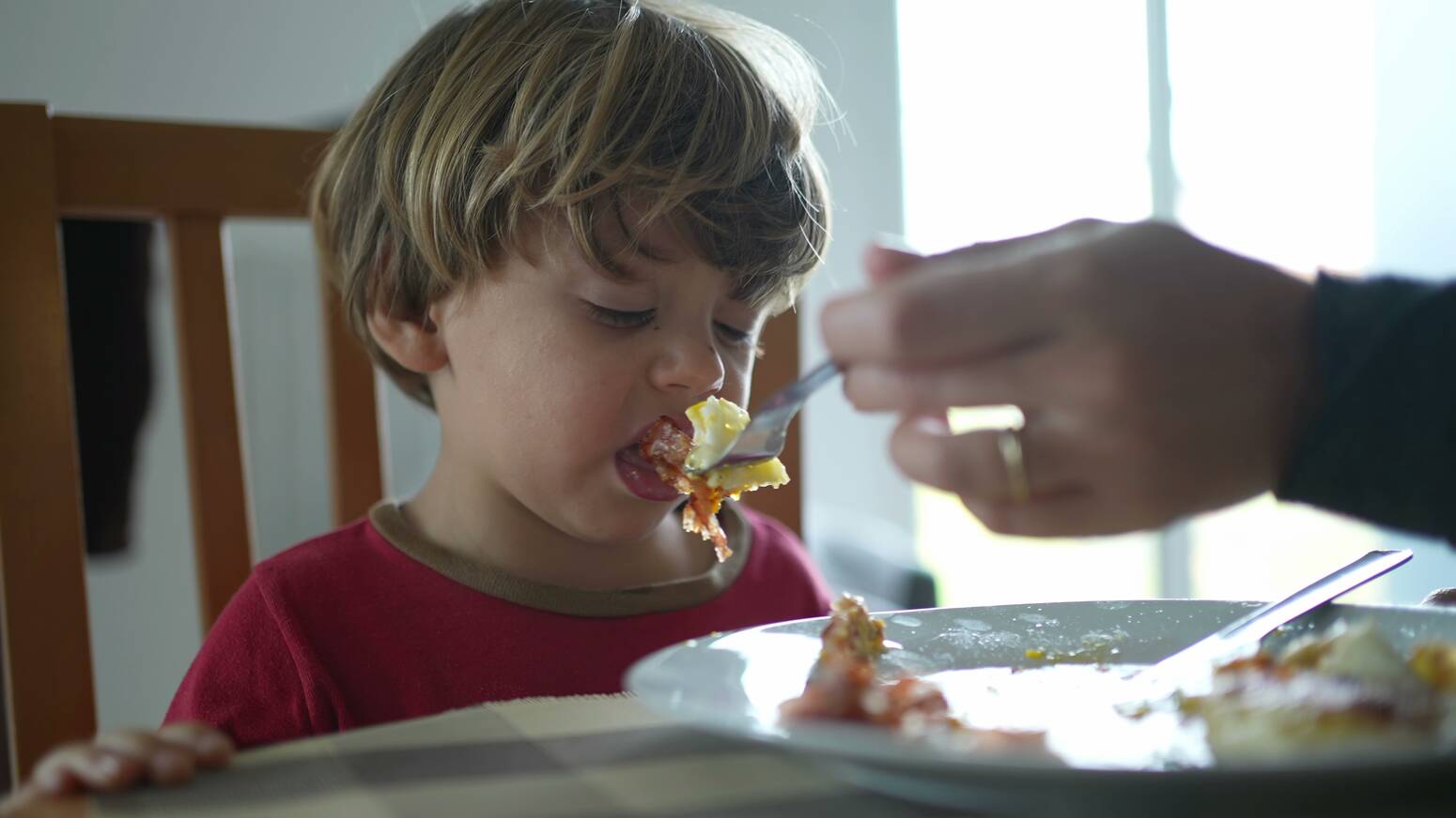 boy being fed food he does not like