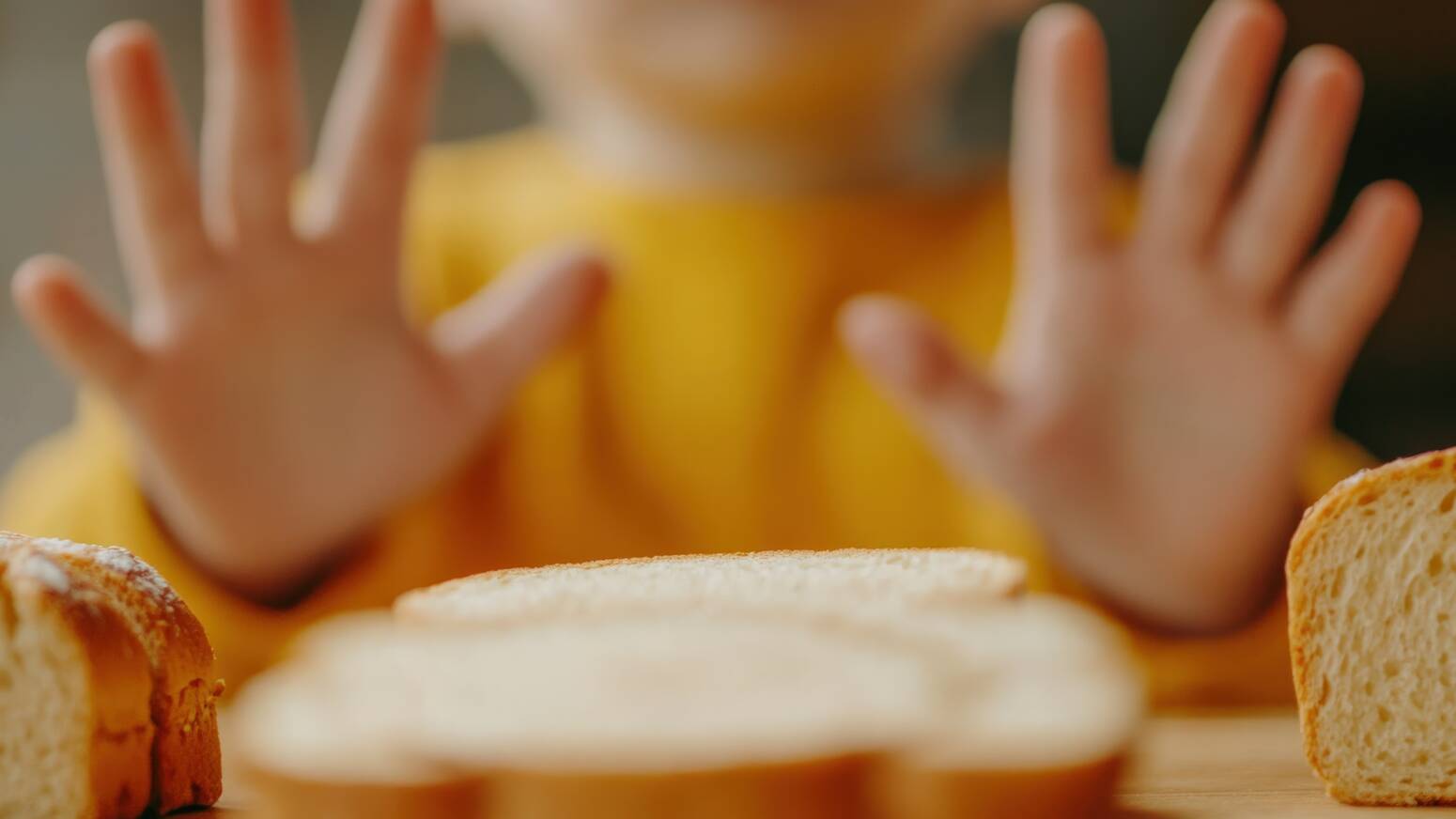 kid sitting at table with hands up