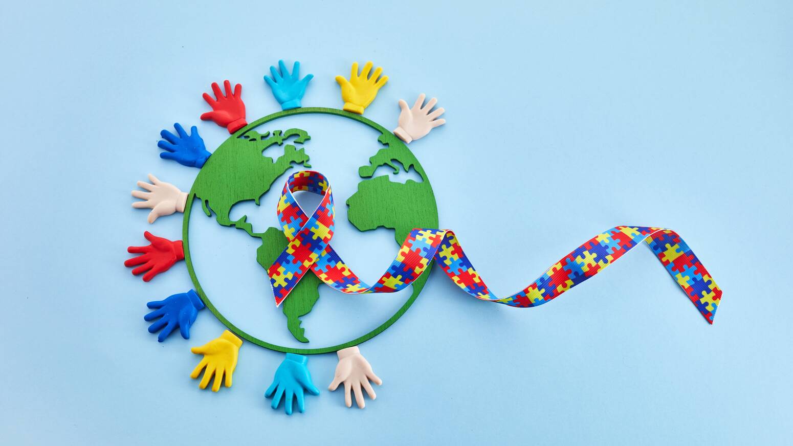 Autism awareness colors with hands and the globe