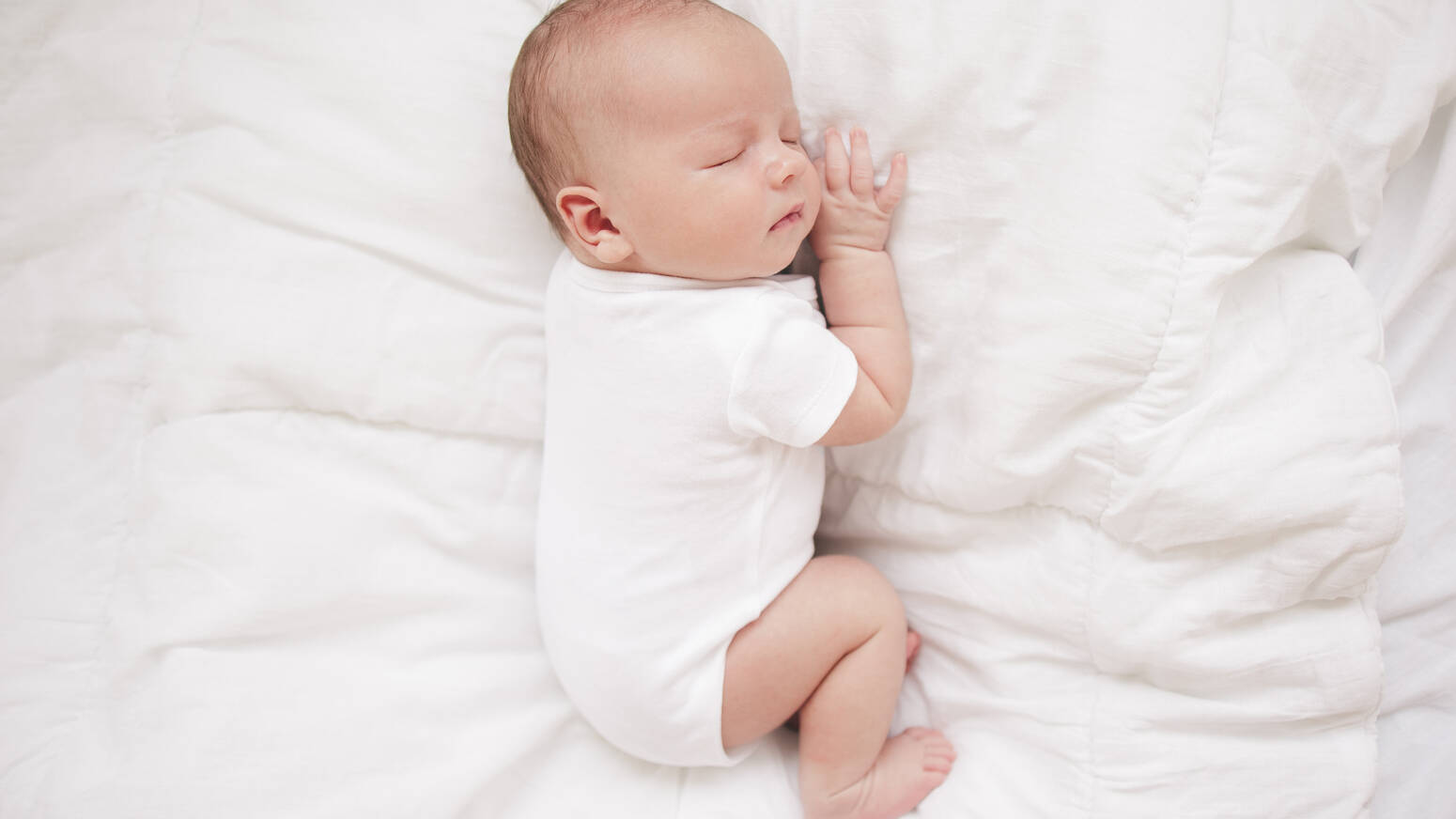 Newborn sleeping on bed