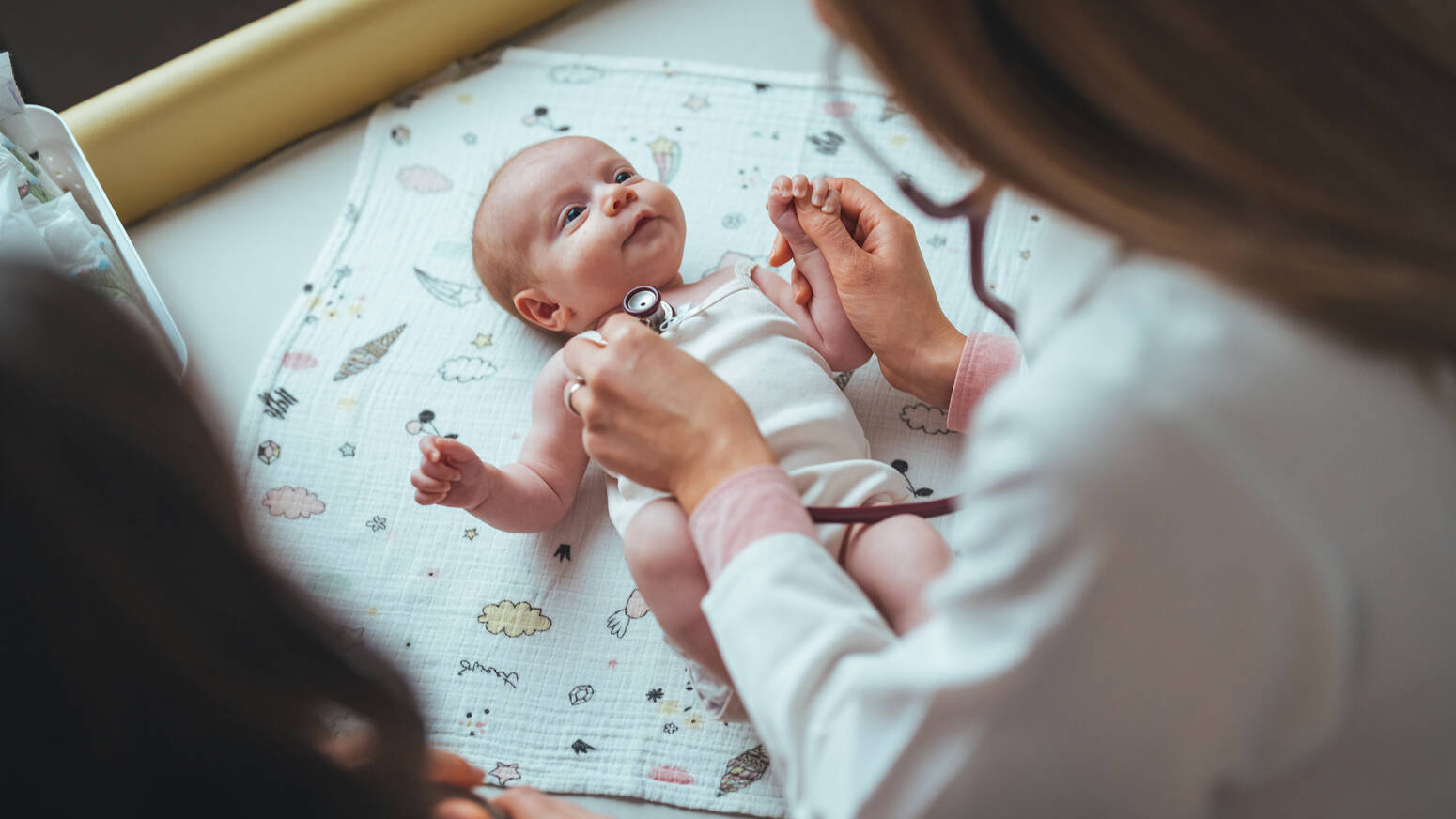 Baby at doctor appointment doctor holding stethoscope to newborn chest