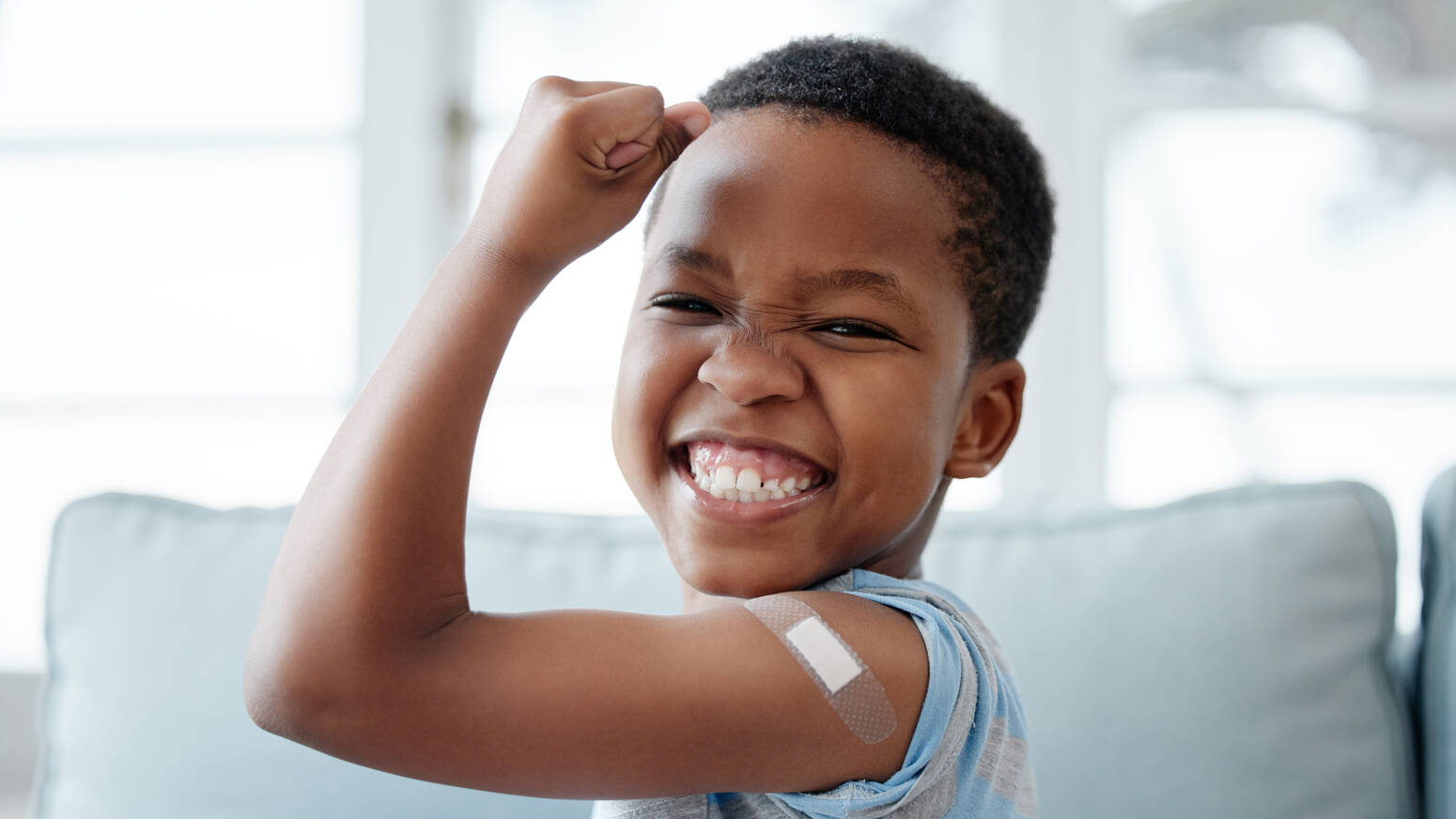 boy holding up arm muscle with bandaid