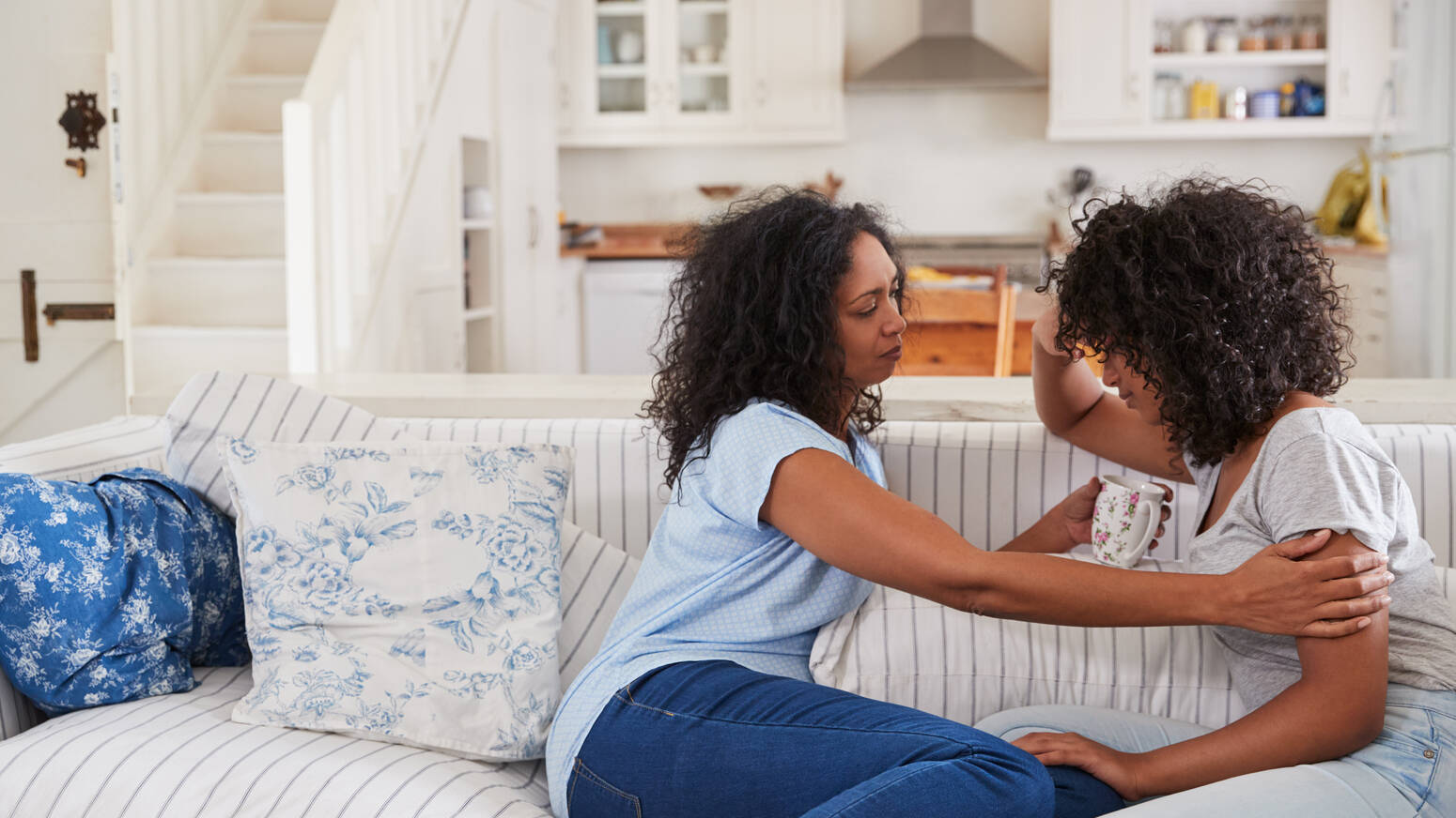 two people sitting on couch comforting