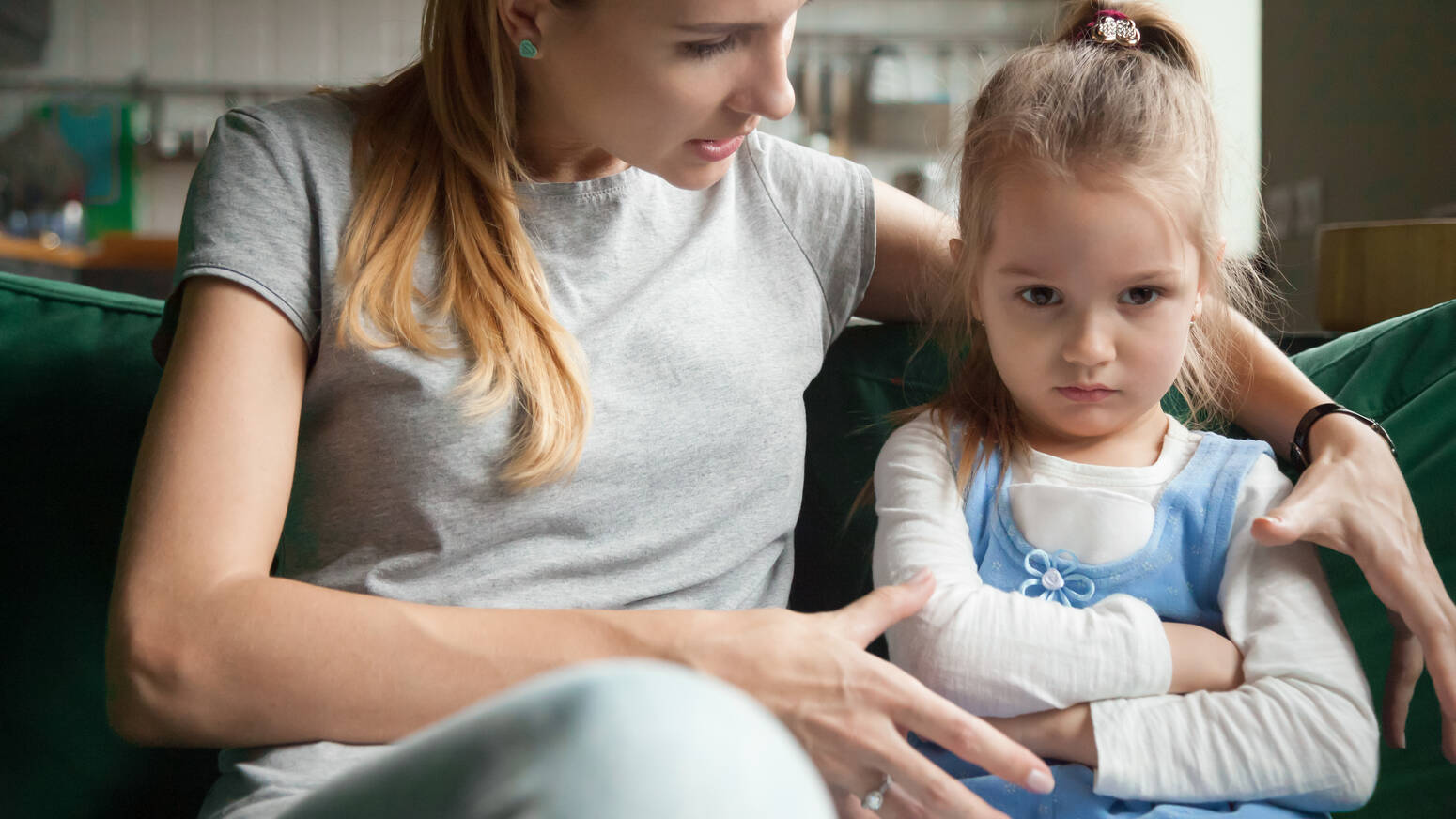 Young child sitting arms crossed with mom trying to comfort