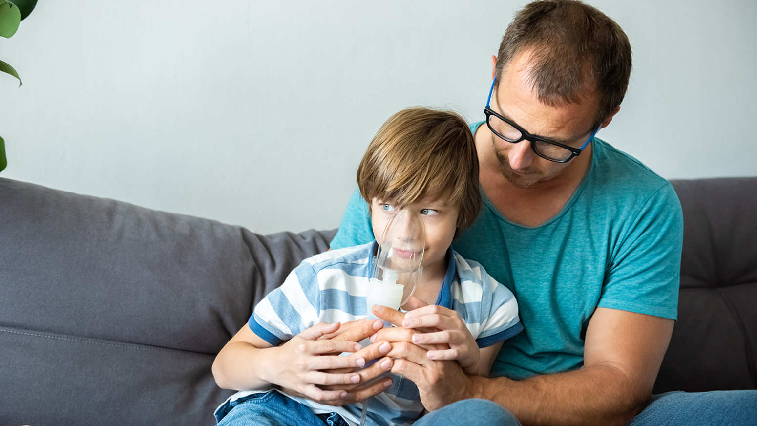Child using nebulizer in father's nap