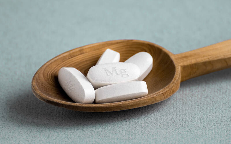 wooden spoon holding Magnesium pills
