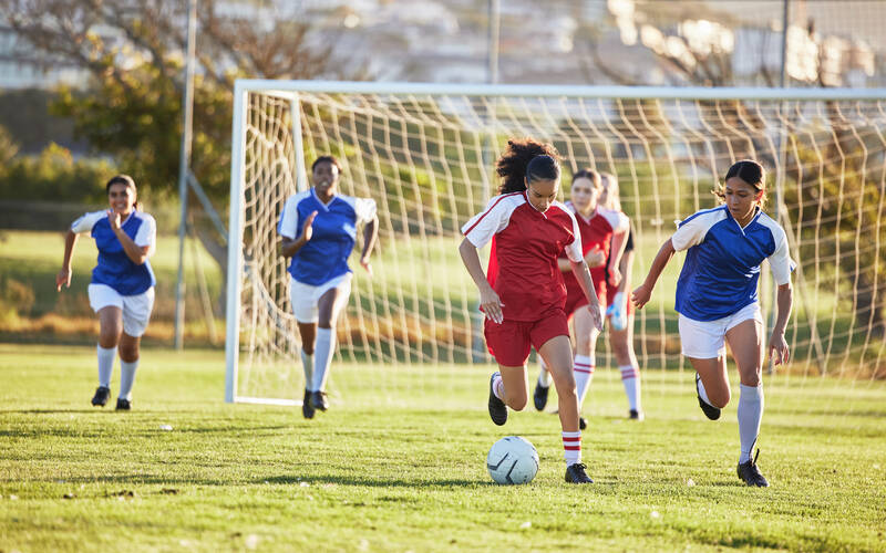 Kids playing soccer two teams kicking ball
