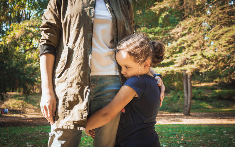 girl holidng onto dads leg