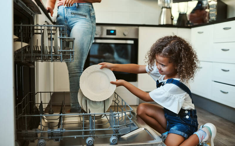 kid loading plates into dishwasher