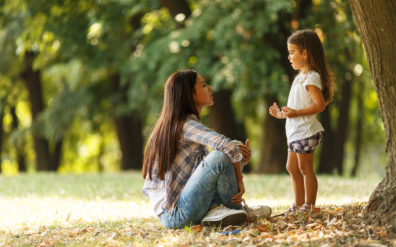 Adult sitting on ground child stand in front 