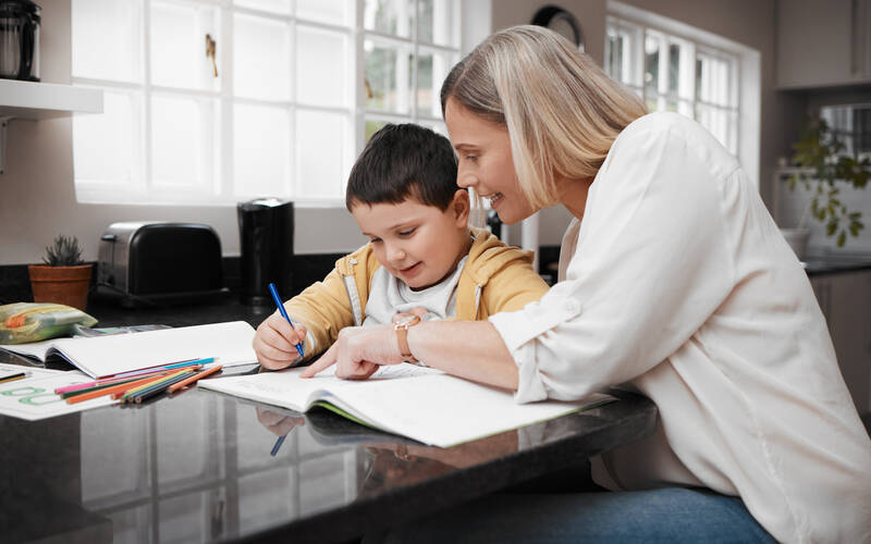 mom and son sitting at table doing schoolwork
