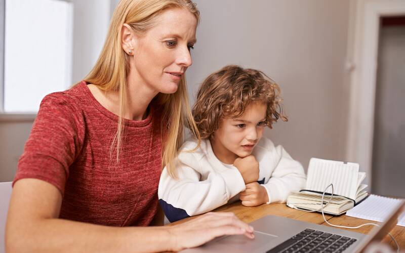 mom and child sitting at a table on a computer