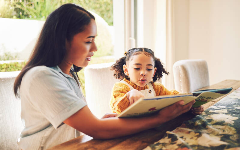 mom and daughter reading at table