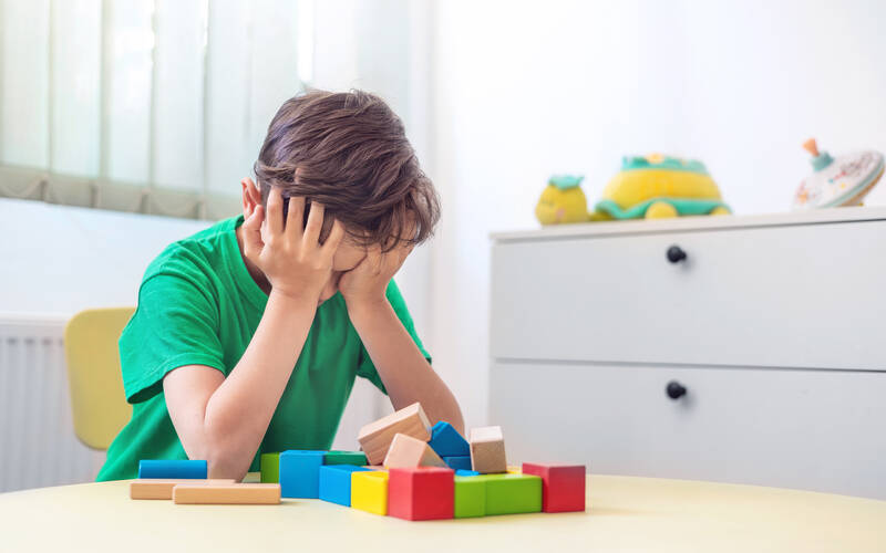 distressed kid at table with blocks