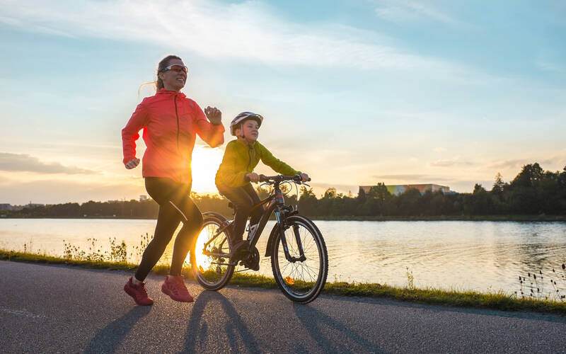 mom running with son on bik in sunset