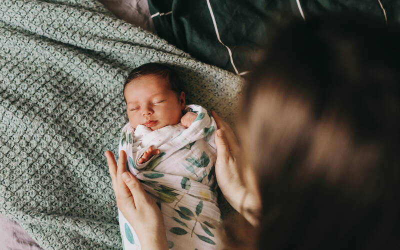 mom looking at swaddled newborn baby from above