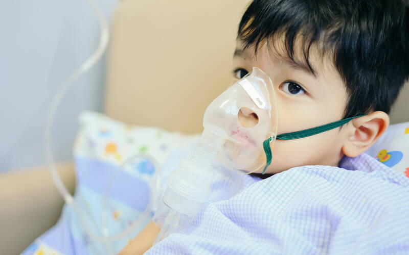 child in hospital bed with breathing mask