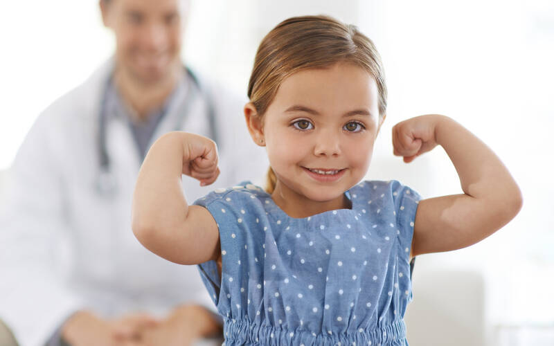 young girl showing arm muscles at doctor