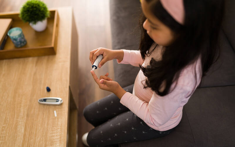 girl sitting at desk testing blood sugar
