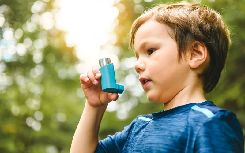 young boy outside holding inhaler