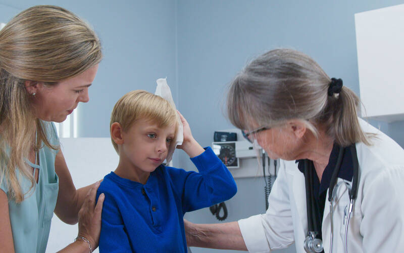 kid at doctor holding head