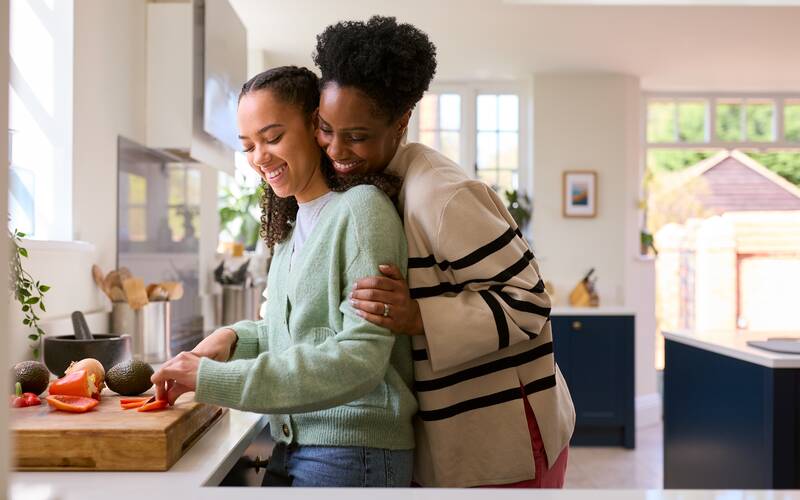 mom with arms around daughter in kitchen