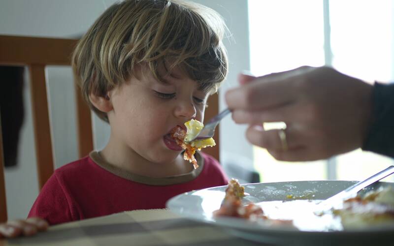 boy being fed food he does not like