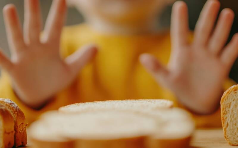kid sitting at table with hands up