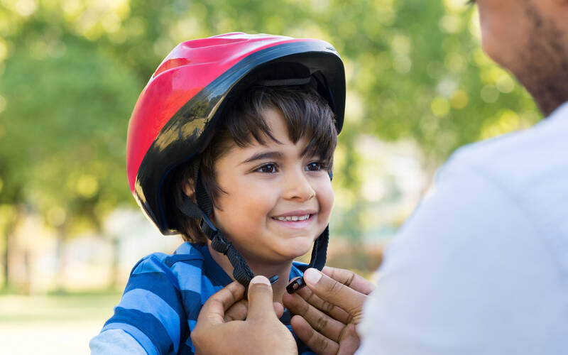 parent-putting-helmet-on-child